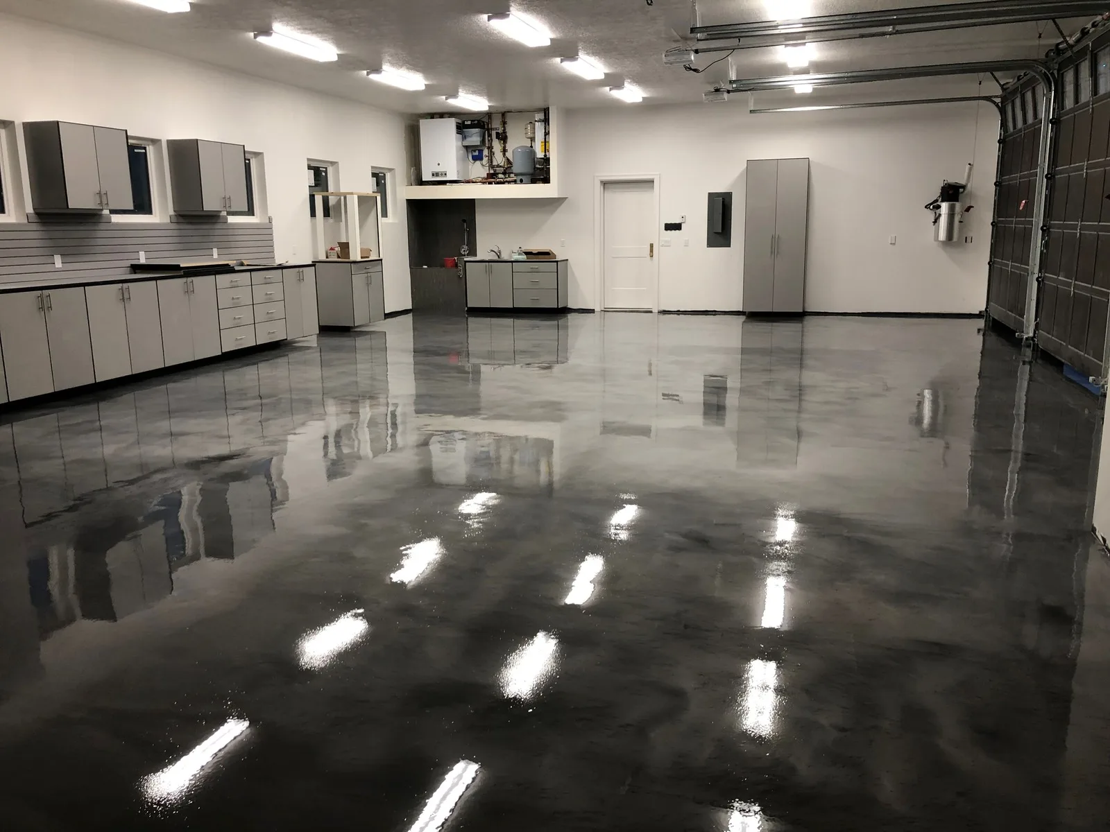 Gloss gray epoxy garage floor with cabinets and lighting