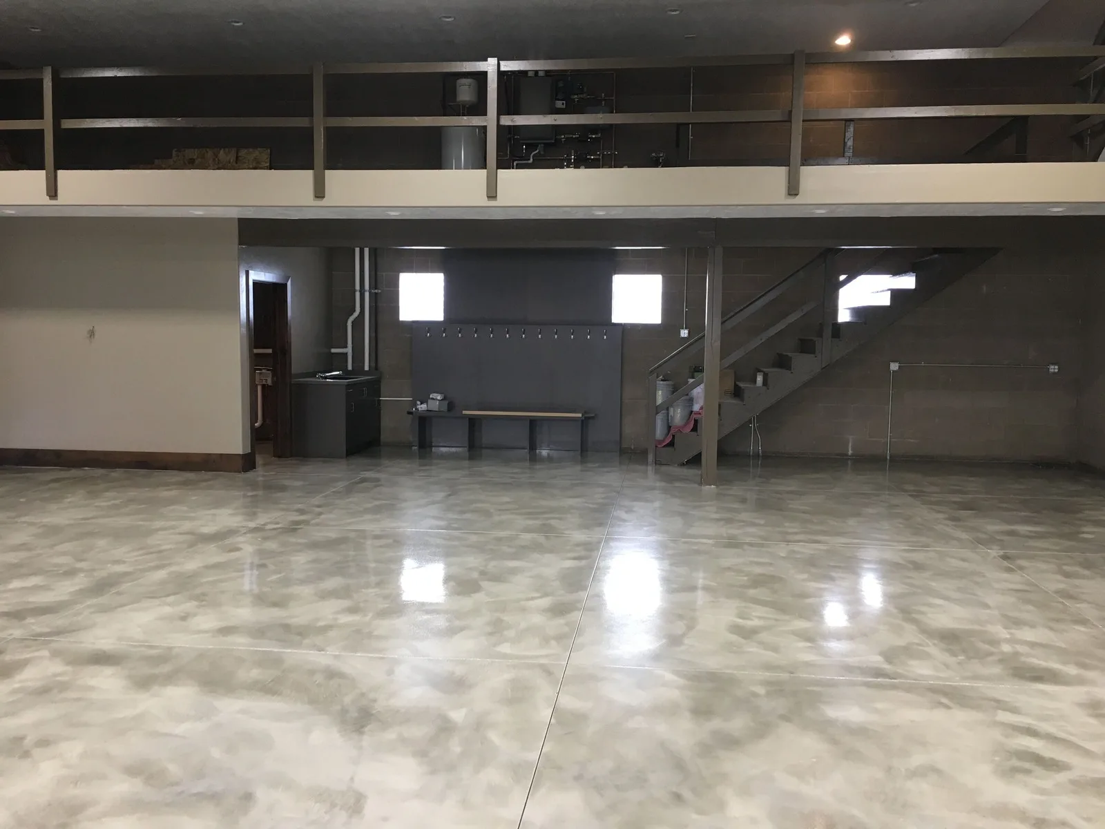 Metallic epoxy floor on a lower level with a mezzanine above