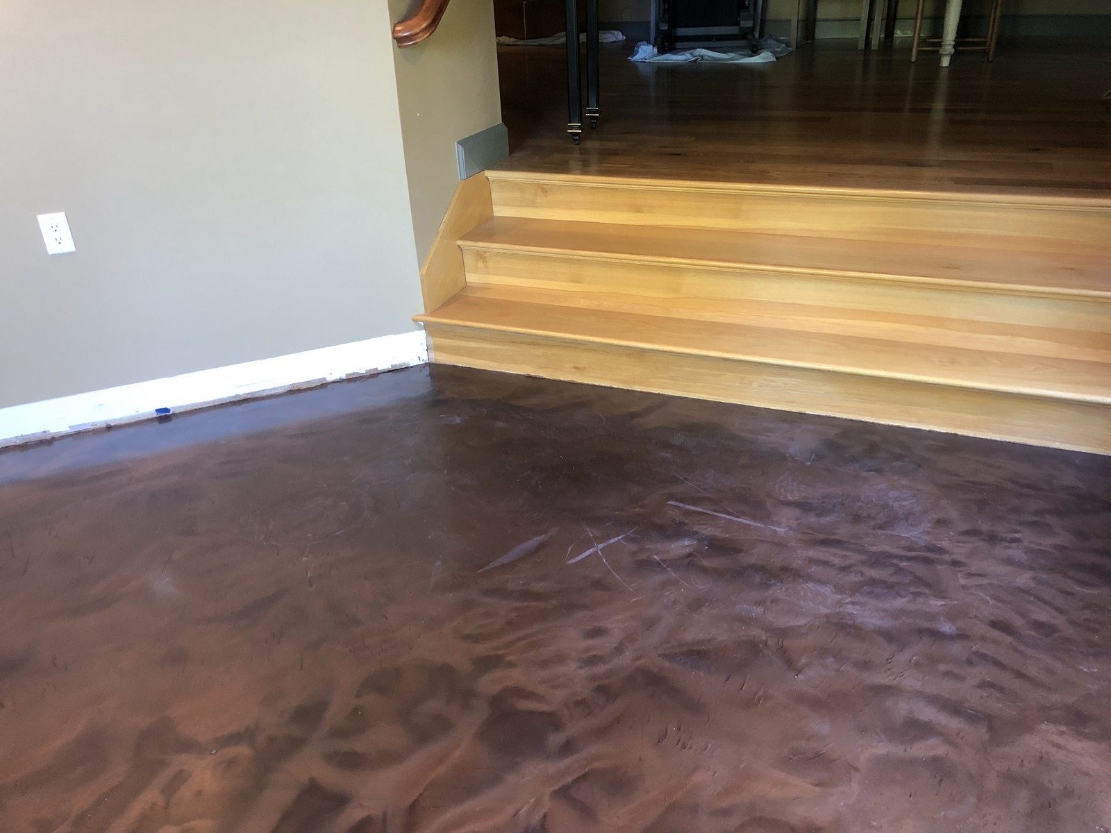 Dark brown stained concrete floor at the foot of a wood staircase in a Utah home